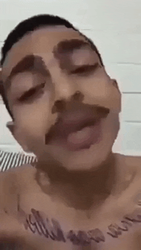 a man with a mustache and a tattoo on his chest is making a face