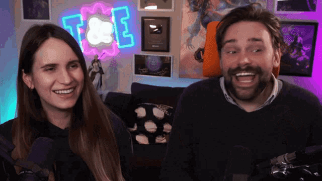 a man and a woman are smiling in front of a sign that says t & e