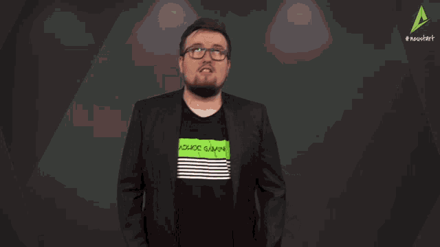 a man wearing a black jacket and a green adhoc gaming shirt