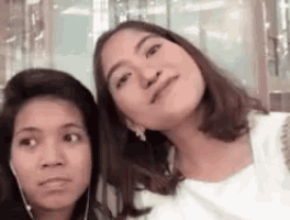 two women are posing for a picture together and one of them is wearing earphones .