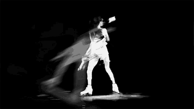 a black and white photo of a woman ice skating on a rink .
