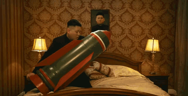 a man is holding a bomb in front of a picture of kim jong-il