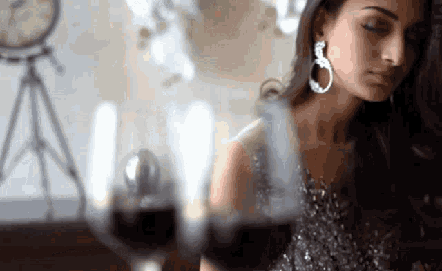a woman in a silver dress is sitting at a table with a glass of wine in front of her