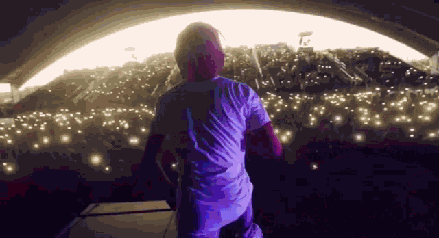 a man in a white shirt is standing on stage in front of a crowd .