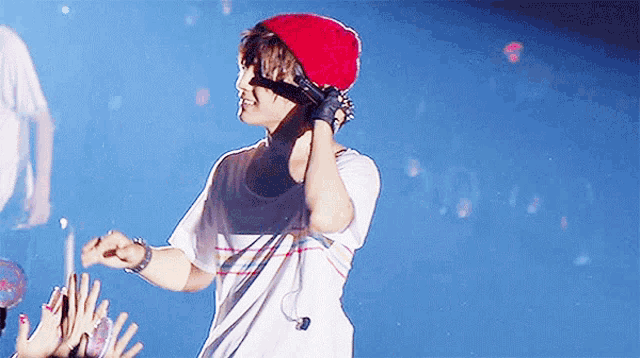 a young man wearing a red hat and gloves is standing on a stage holding a microphone .
