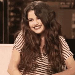 a woman with long hair and a striped shirt is smiling .