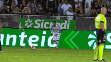 a soccer player is kicking a ball in front of a sicredi sign