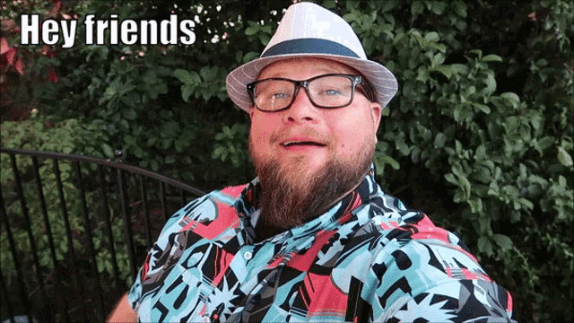 a man wearing a hat and glasses says " hey friends "