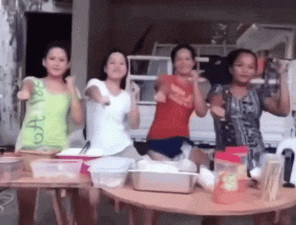 a group of women are standing around a table with one wearing a green tank top that says ' oa ' on it