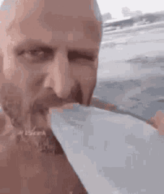a man with a beard is drinking water from a bottle while standing in the water .
