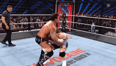 two men are wrestling in a wrestling ring with the word cocaine on the floor