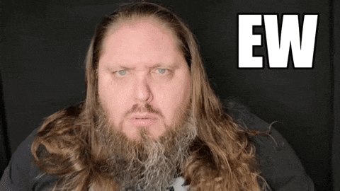 a man with long hair and a beard is looking at the camera with the word ew behind him