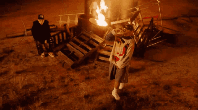 a man stands in front of a fire wearing a sweatshirt that says supreme on it