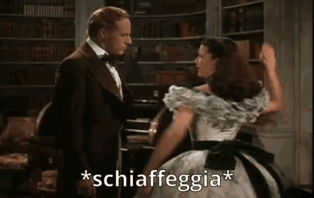 a man in a tuxedo and a woman in a white dress are dancing in a room .