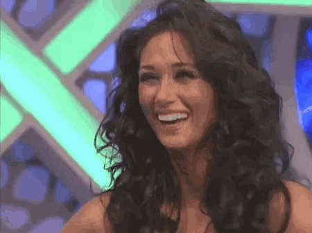a woman with long dark hair is smiling in front of a green light