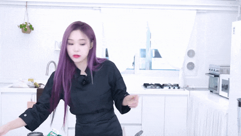 a woman with purple hair is standing in a kitchen