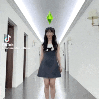 a woman in a black dress is standing in a hallway with a green diamond on top of her head