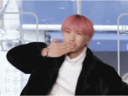 a man with pink hair is blowing a kiss with his hand