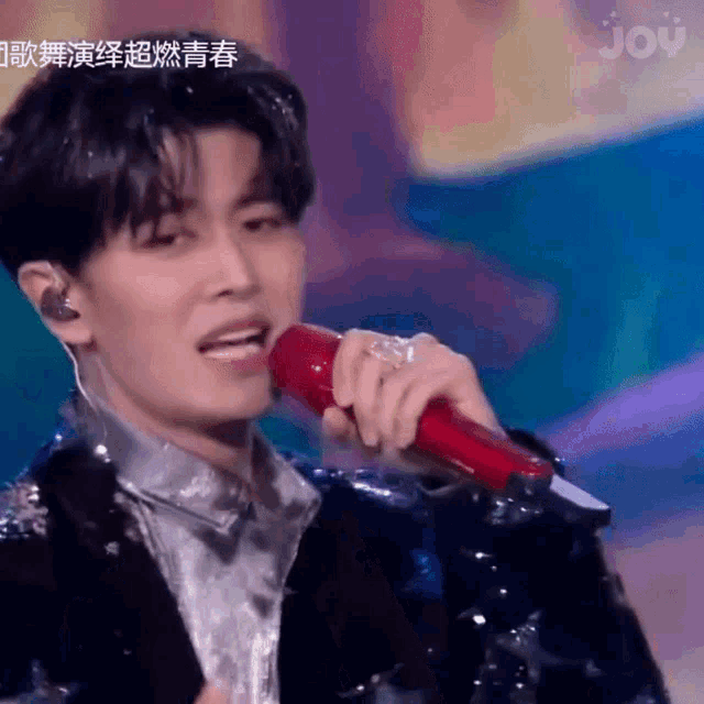 a man is singing into a red microphone with joy written on the bottom