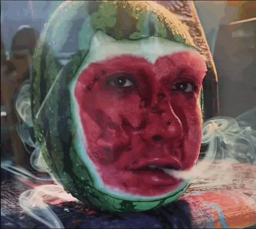 a person wearing a watermelon mask smoking a cigarette