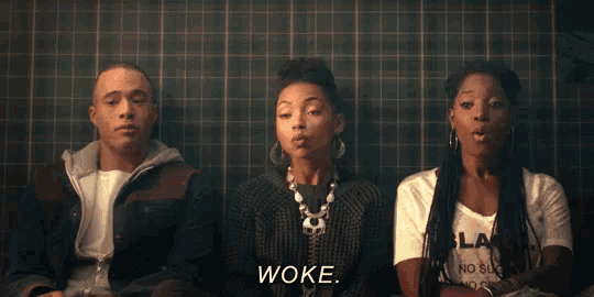 a group of people are sitting in front of a tiled wall and one of them is saying woke
