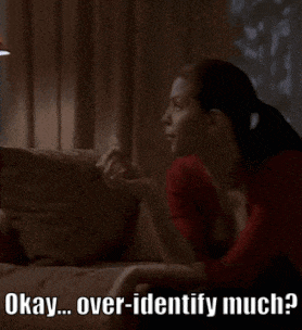 a woman is sitting on a couch with the words okay over-identify much