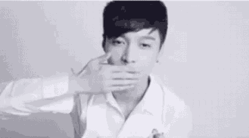 a black and white photo of a man in a white shirt pointing at the camera .