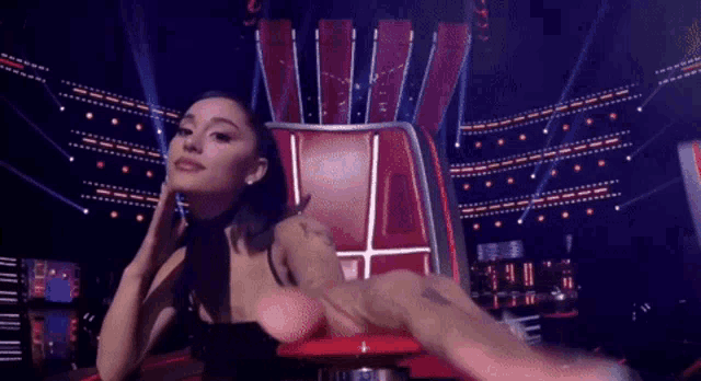 a woman is sitting in a red chair on stage
