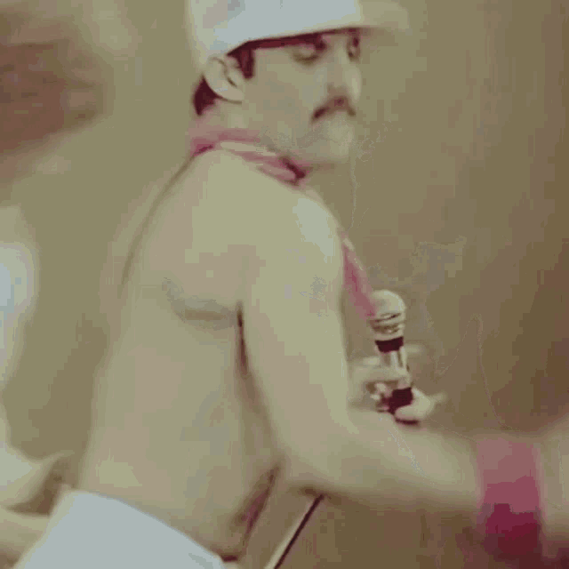 a man without a shirt is holding a microphone and wearing a white hat with the letter c on it