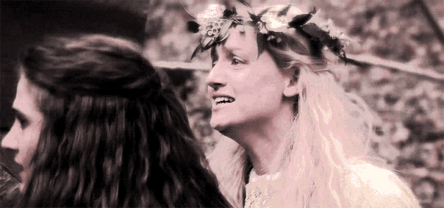 a woman with a flower crown on her head looks at another woman