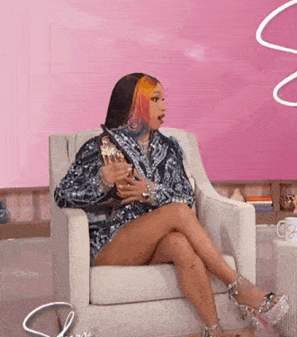 a woman is sitting in a chair with her legs crossed and holding a trophy