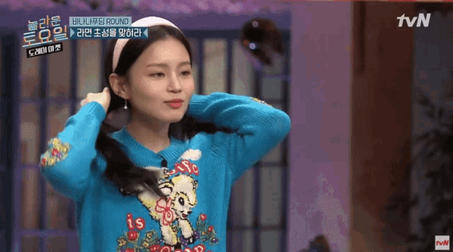 a woman wearing a blue sweater and a white headband with tvn written on the bottom right