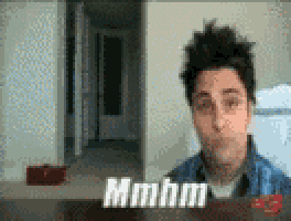 a man is making a funny face while sitting at a table with the words mmmm written on it