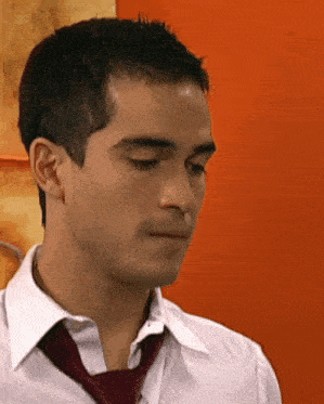 a man wearing a white shirt and a red tie looks down