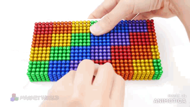 a person is playing with a rainbow colored stack of magnets