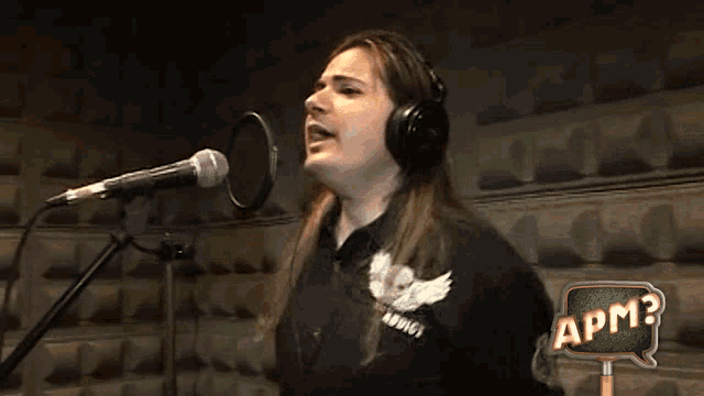 a woman singing into a microphone with apm written on the bottom