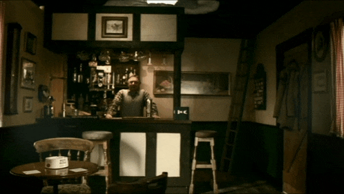 a man stands behind a bar with a sign on the wall that says ' a '