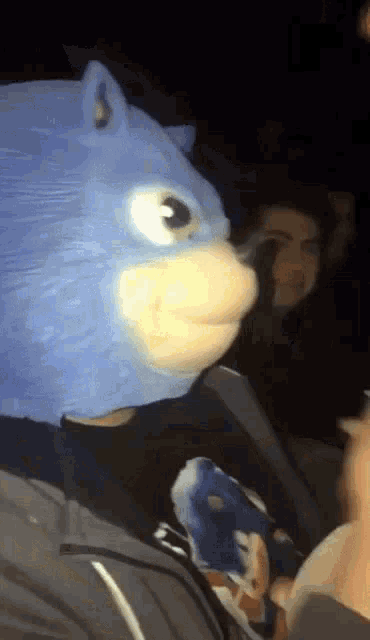 a person is wearing a sonic the hedgehog mask while sitting in a dark room .