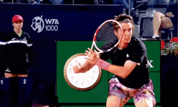 a tennis player swings a racket in front of a wta 1000 sign
