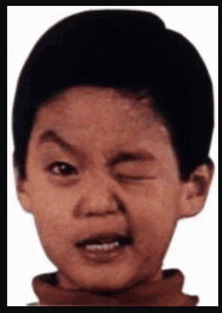 a young boy is making a funny face with one eye open .