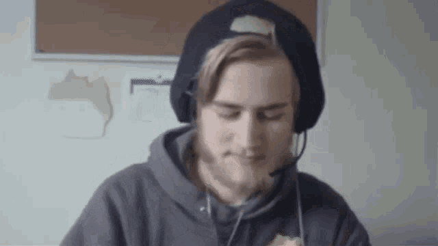 a man wearing headphones and a beanie is sitting at a desk .