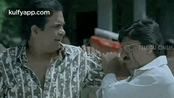 two men are standing next to each other and talking to each other in a movie .