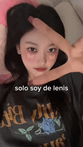 a girl wearing a black shirt that says solo soy de lenis makes a peace sign