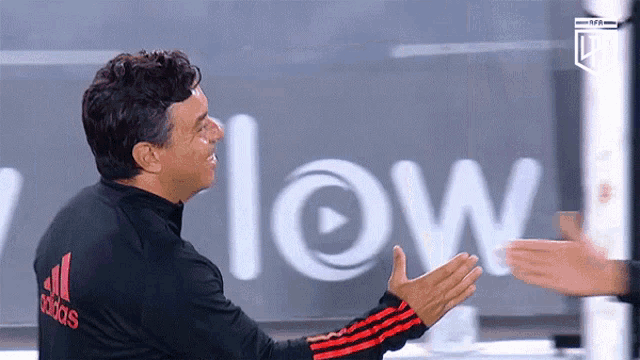 a man wearing a black and red adidas jacket
