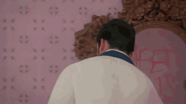 a man standing in front of a mirror with the word jesus written on the wall behind him