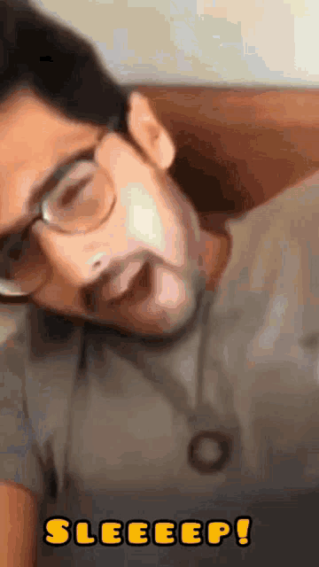a man with glasses and a beard is laying on a couch with the words " sleeeeep " above him