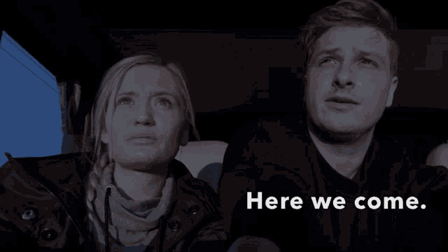 a man and a woman in a car with the words here we come behind them