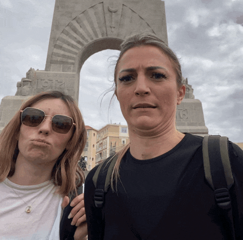two women are making funny faces in front of a statue that says 1912
