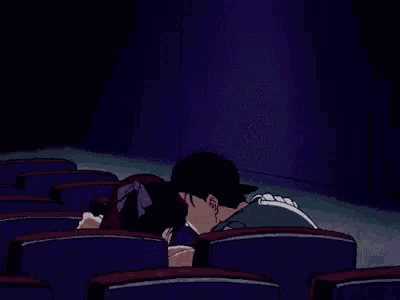 a man and a woman are sitting in a theater with their arms outstretched .