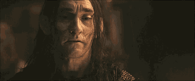 a man with long hair is looking at the camera with a serious look on his face